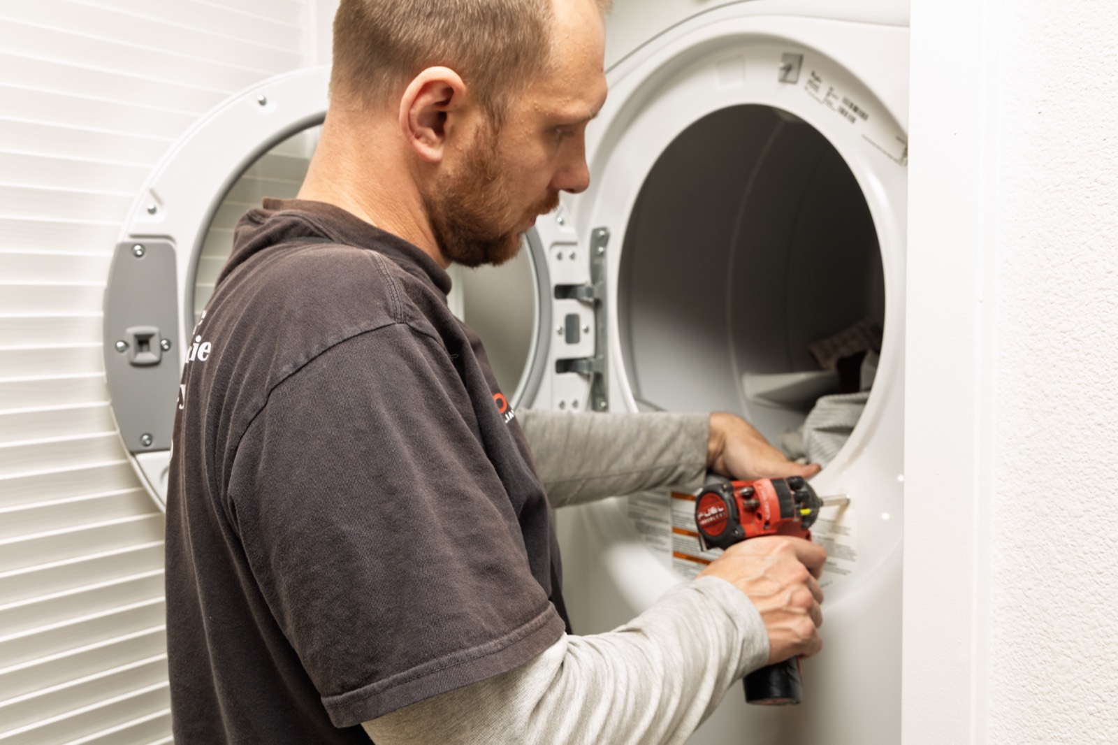 Fortex technician repairing a dryer with a power drill