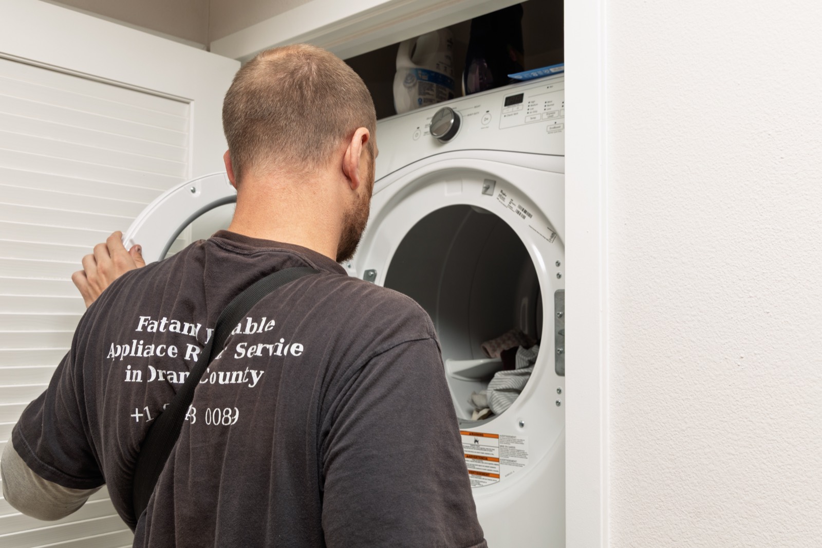 Fortex technician in a branded shirt repairing a stacked dryer