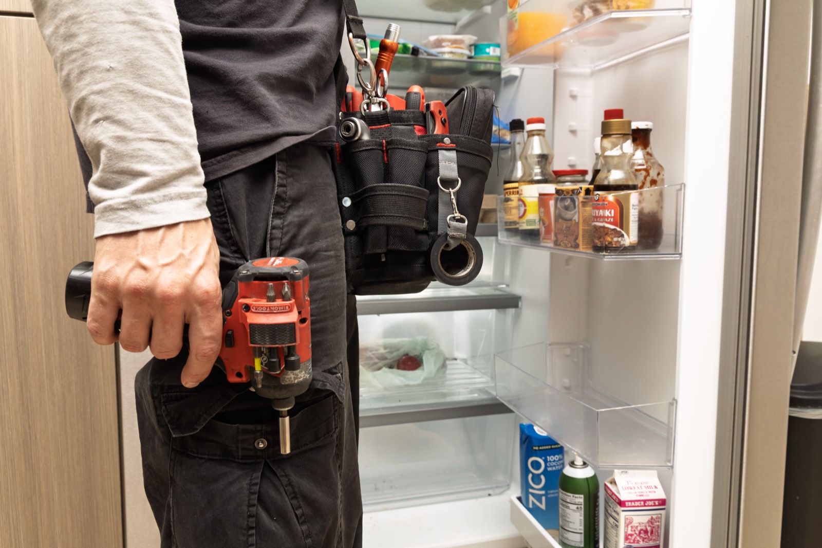 Technician repairing an open side-by-side refrigerator