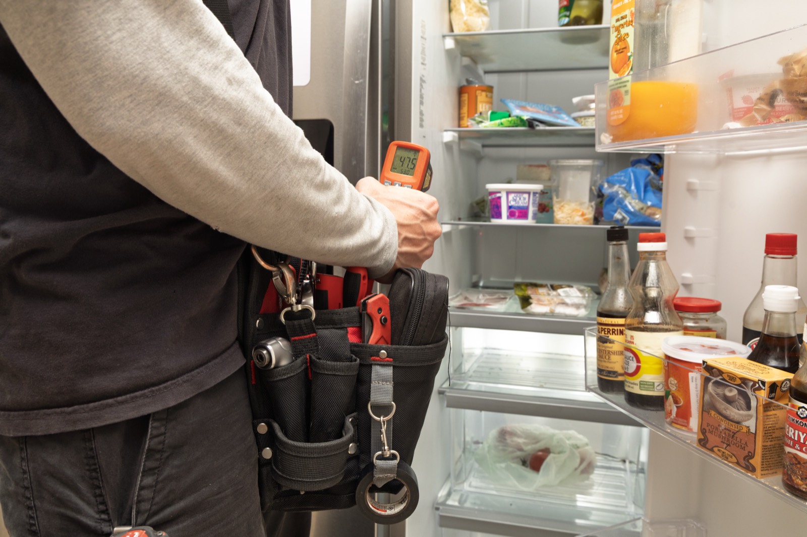 Technician checking refrigerator temperature with an infrared thermometer