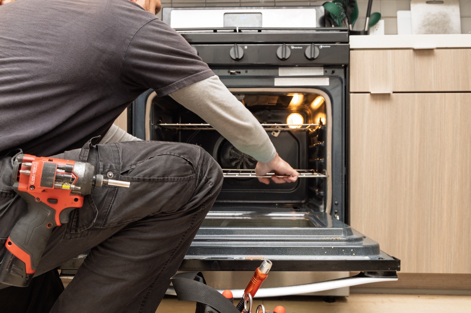 Fortex technician repairing an oven with a power drill